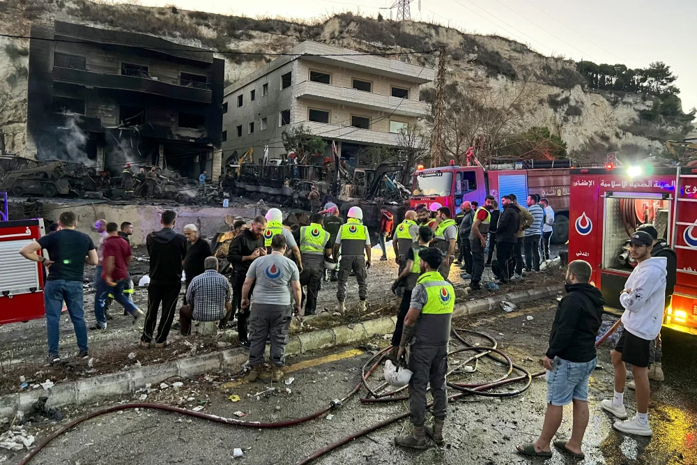 Rescuers and first-responders stand outside a damaged building following an overnight Israeli strike in Al-Msayleh area in southern Lebanon on October 11, 2025.Mahmoud Zayyat / AFP - Getty Images
